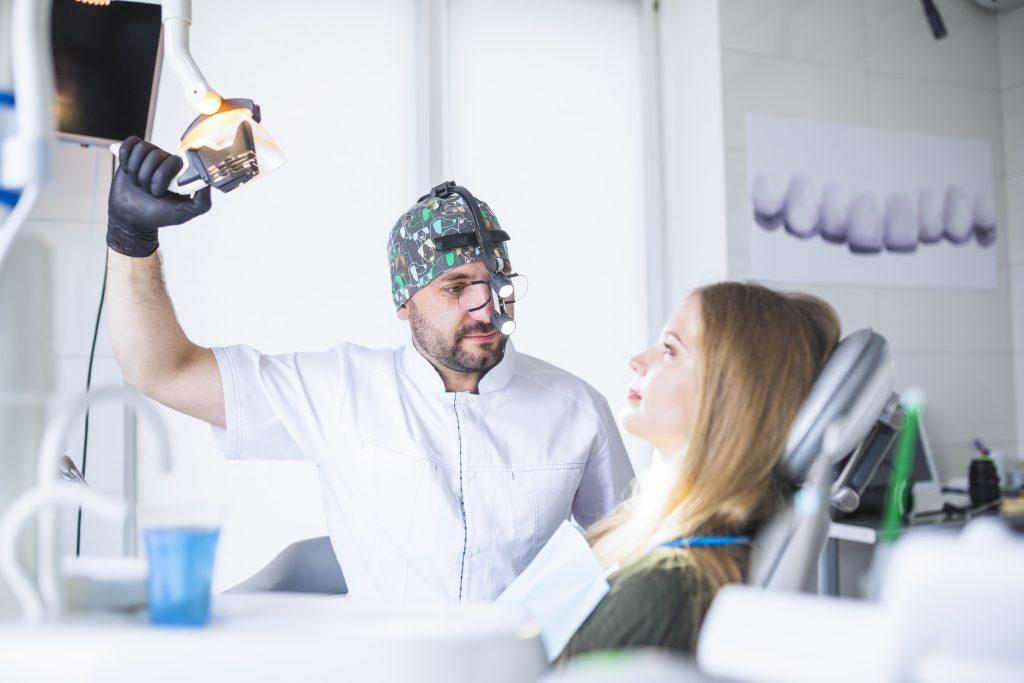 dentist-wearing-dental-loupe-binoculars-treating-female-patient