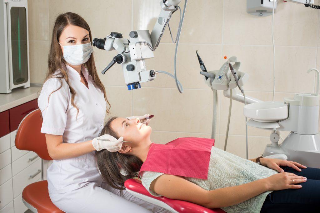Woman dentist in her office treating female patient